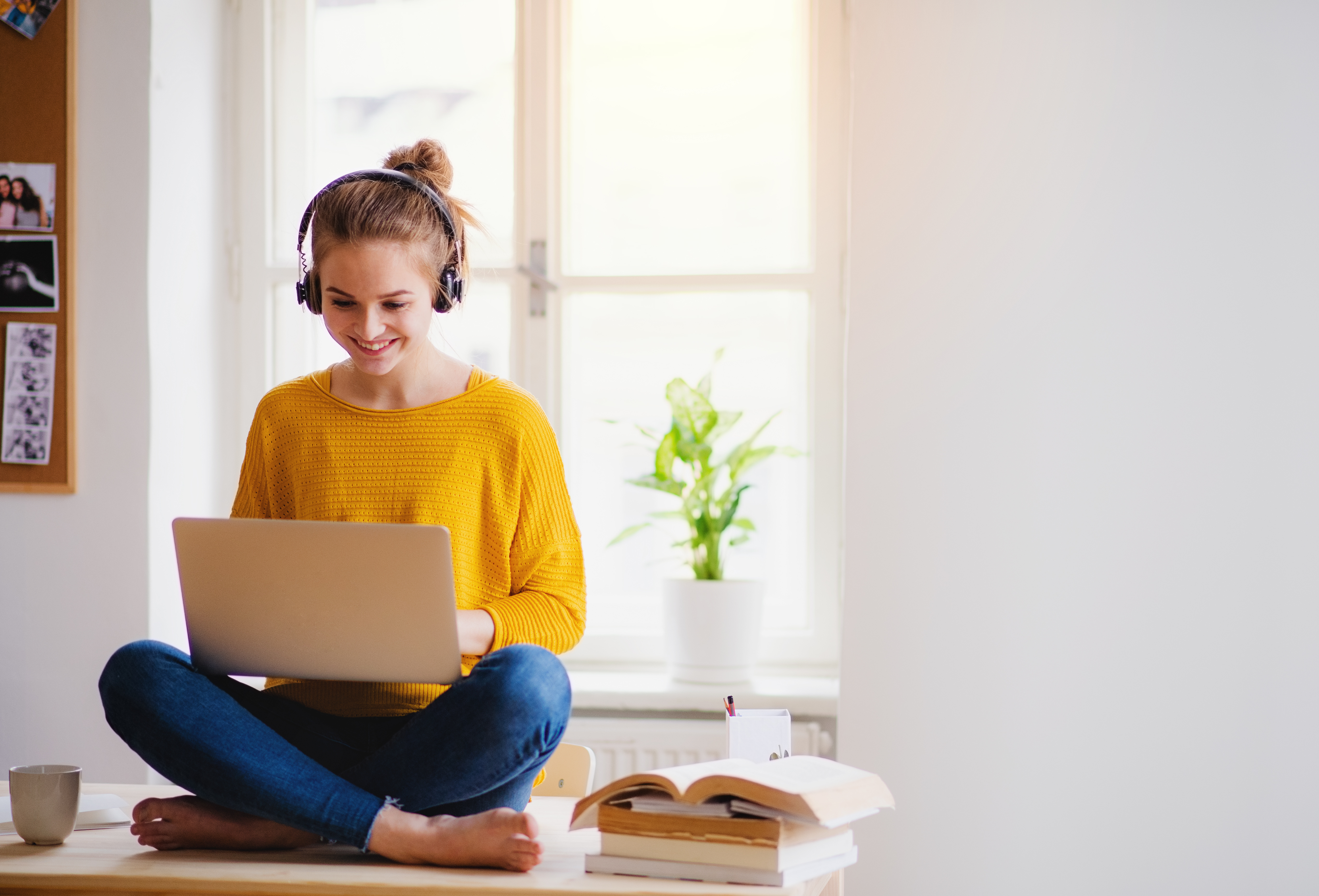 A prospective RBT wearing headphones studies from her laptop with a stack of books nearby.